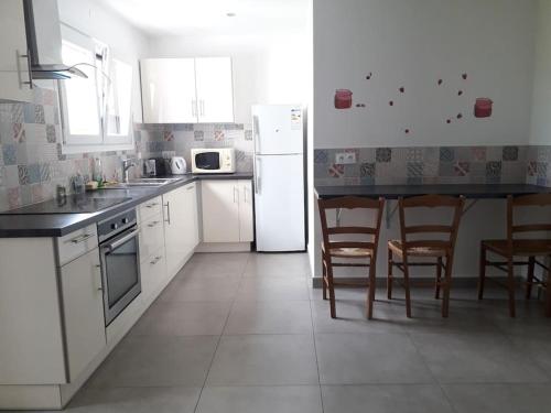 - une cuisine avec des appareils blancs, une table et des chaises dans l'établissement Le Jirani 90m2 calme jardin privé proche Le Phare, à Chambéry