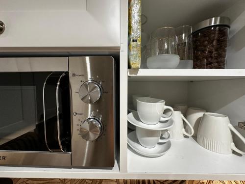 two open cabinets with cups and plates and a microwave at Air Suite in Spáta