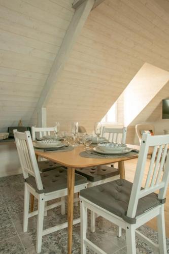 une table à manger avec des chaises et une table en bois avec des verres dans l'établissement La boulangerie appartement 2, à Janzé