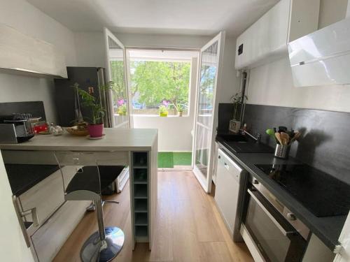 une cuisine avec des comptoirs noirs et une grande fenêtre dans l'établissement Flat air conditioning 4 people near stadium beach, à Marseille