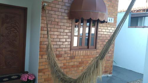 a hammock attached to a brick wall with a window at Casa Rua Salvia, Jd Tulipa in Holambra