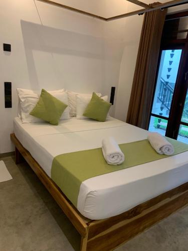 a bedroom with a large bed with green and white pillows at Summer Time Hiriketiya in Dickwella