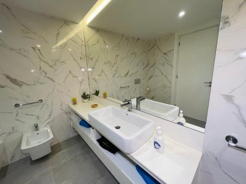 a white bathroom with a sink and a mirror at Hortas Residence 13 in Funchal