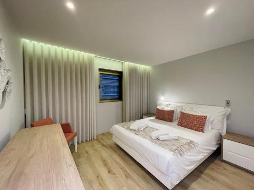 a bedroom with a large white bed and a table at Hortas Residence 13 in Funchal
