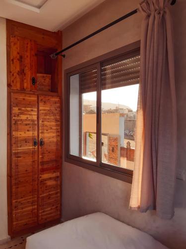 a bedroom with a window with a bed and a dresser at Imsouane WOOD HOUSE in Imsouane