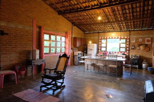 a large room with a kitchen and a chair in it at Chalé com Vista Privilegiada in Pilões