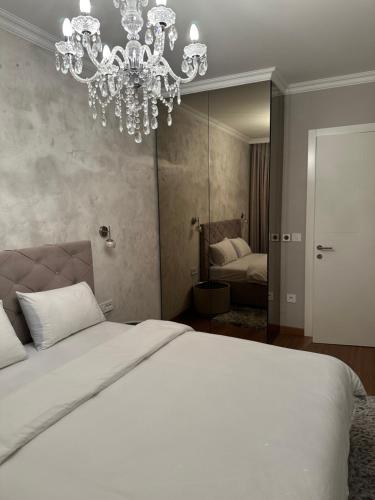 a bedroom with a large white bed and a chandelier at Pupin Palace Apartments in Novi Sad