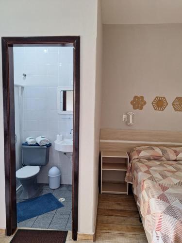 a bedroom with a bed and a bathroom with a sink at Hotel Itamiaru in Iguape