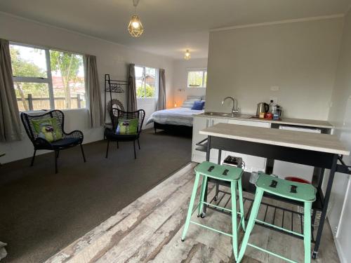 a kitchen and living room with a table and two stools at Relax Inn Beach Studio in Motueka
