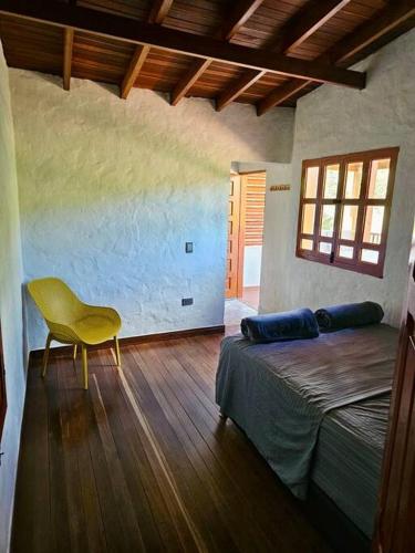 a bedroom with a bed and a yellow chair at Tranquilidad y Naturaleza Cabaña Concepción in Concepción