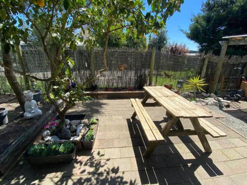a wooden picnic table in a garden with a tree at Relax Inn Beach Studio in Motueka