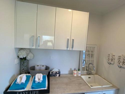 a kitchen with white cabinets and a sink at Relax Inn Beach Studio in Motueka