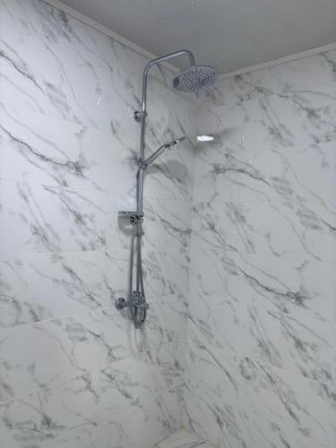 a shower in a bathroom with white marble walls at Shahdag S&R House in Qusar