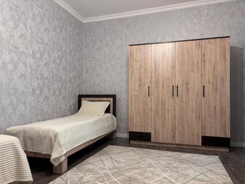 a bedroom with a bed and a wooden cabinet at Shahdag S&R House in Qusar