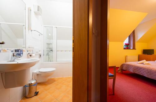 a bathroom with a sink and a toilet and a bed at Vila Park in Tatranská Lomnica