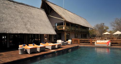 a swimming pool with lounge chairs and a building at Cresta Mowana Safari Resort & Spa in Kasane