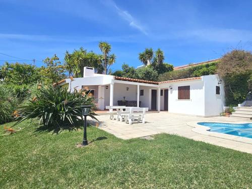a white house with a patio and a swimming pool at 4 chambres, piscine Casa Oleias by SesimbraSunSea in Sesimbra