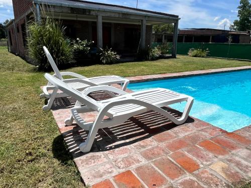 2 sedie da giardino bianche sedute accanto alla piscina di Salta Casa El rodeo a Salta