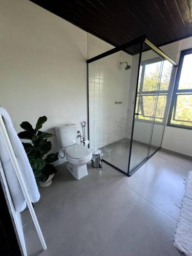 a bathroom with a toilet and a glass shower at Chácara da Aráucária - sítio privativo com piscina, churrasqueira e área verde in Presidente Lucena
