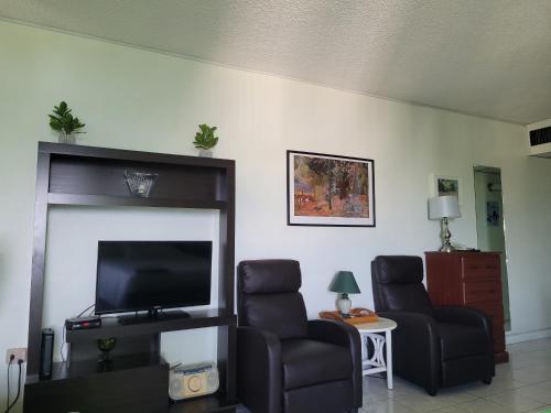 a living room with two chairs and a flat screen tv at Irresistible View-Mobay Club 1408 in Montego Bay