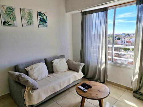 ein Wohnzimmer mit einer Couch und einem Tisch und einem Fenster in der Unterkunft El departamento de Mel in Villa Luzuriaga