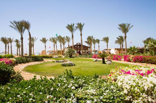 a garden with palm trees and flowers in a resort at Green Sudr Kitesurfing Hotel in Raʼs Matarma