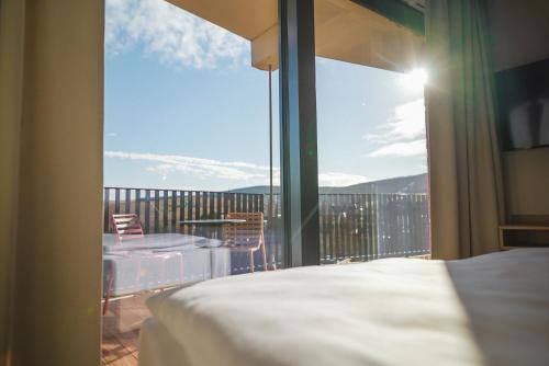 a bedroom with a view of a balcony with a bed at Summit of Saxony Resort Oberwiesenthal in Kurort Oberwiesenthal