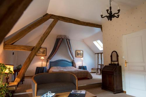 - une chambre mansardée avec un lit et une table dans l'établissement Château de la Frégeolière, à Theillay