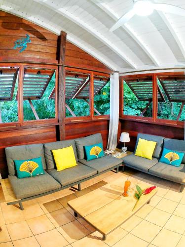 a living room with a couch and some windows at Duplex Toti la - TropicalKaz Guadeloupe in Bouillante