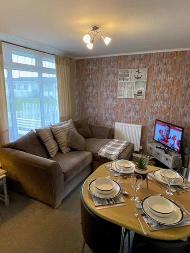 a living room with a couch and a table at Sandy Paws in Trusthorpe