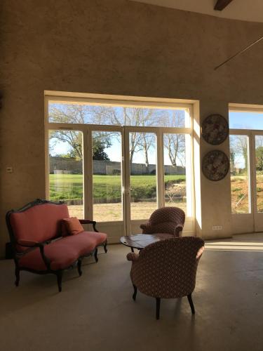 a living room with chairs and a table and windows at Les Granges Pelloquin in Bernières-sur-Mer