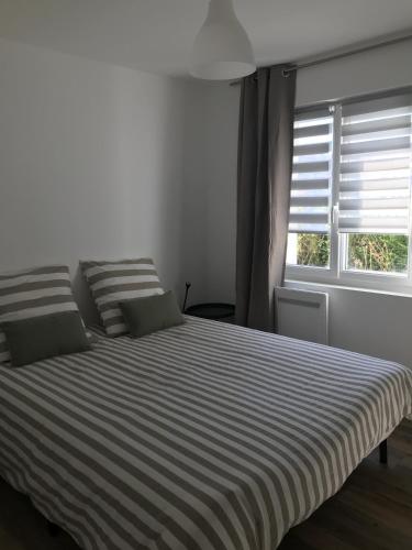 a bedroom with a bed with striped sheets and a window at Un sejour a Cabourg in Cabourg