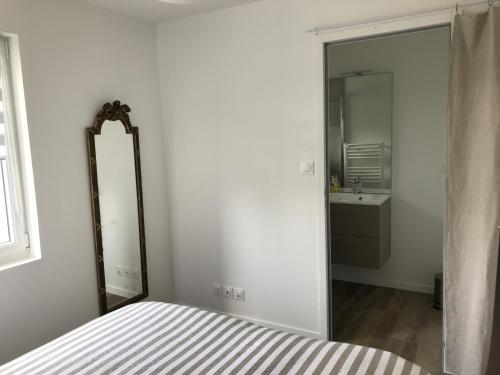 - une chambre avec un miroir, un lit et un lavabo dans l'établissement Un sejour a Cabourg, à Cabourg