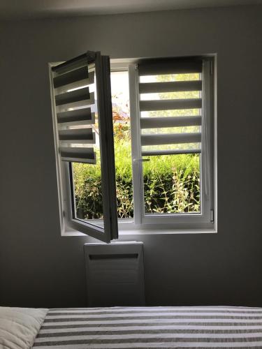 - une chambre dotée d'une fenêtre avec volets et d'un lit dans l'établissement Un sejour a Cabourg, à Cabourg