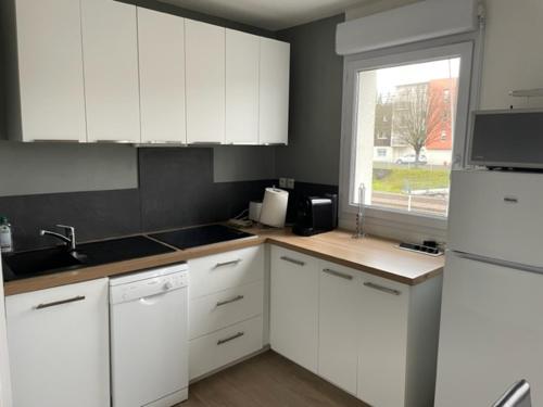 une cuisine avec des armoires blanches et une fenêtre dans l'établissement Leclerc 217, à La Roche-sur-Yon