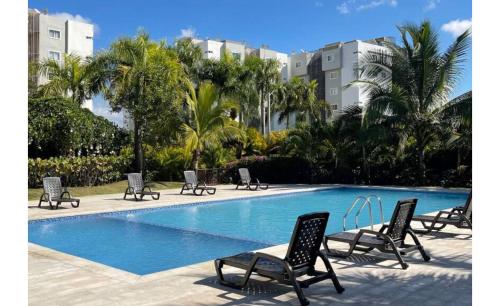 a swimming pool with chairs and trees and buildings at Residencial Mediterraneo in Santiago de los Caballeros