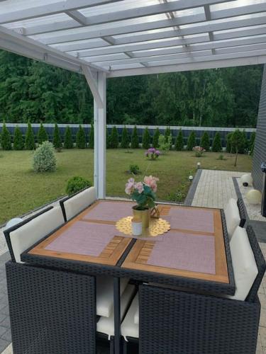 a wooden table with a vase of flowers on a patio at Villa Stella Strandnah in Gryfice