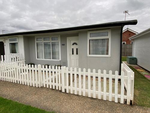 a small house with a white fence in front of it at Sandy Paws in Trusthorpe
