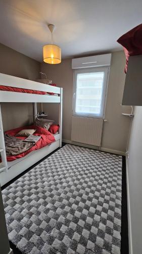 une petite chambre avec deux lits superposés et une fenêtre dans l'établissement Le Repaire Malouin, à Saint-Malo