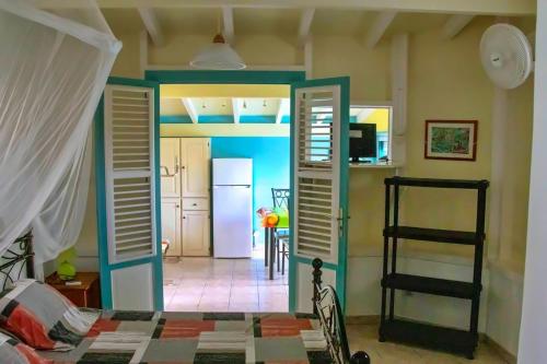 a room with a bed and a kitchen with a refrigerator at Les marches de Paulina in Sainte-Luce