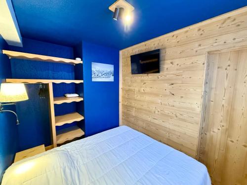 - une chambre avec des murs bleus et un lit blanc dans l'établissement Appartement aux Orres 1800 en RDC, aux Orres