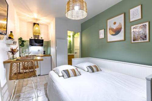 a bedroom with a white bed and a kitchen at Le Papucie, Studio Cosy en Plein Cœur de Sarlat in Sarlat-la-Canéda