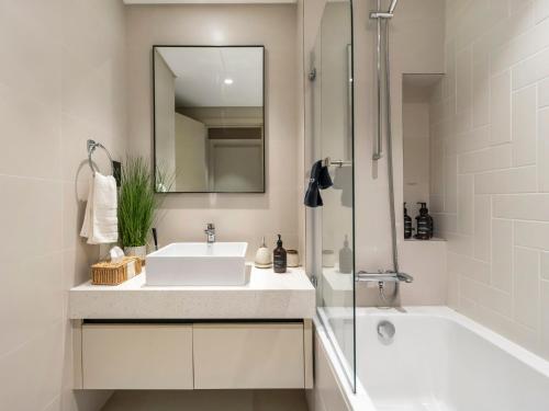 a bathroom with a sink and a mirror and a tub at Cozy One Bedroom on the Beach in Dubai Harbour - Prestige Retreats in Dubai
