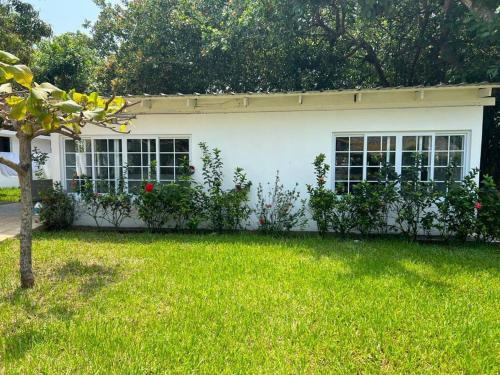 a white house with a yard with green grass at Monterico- Casa en la playa Pitas2 in El Garitón