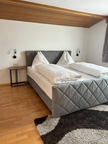 a bedroom with a large bed with a gray headboard at Pension Alpina in Roppen
