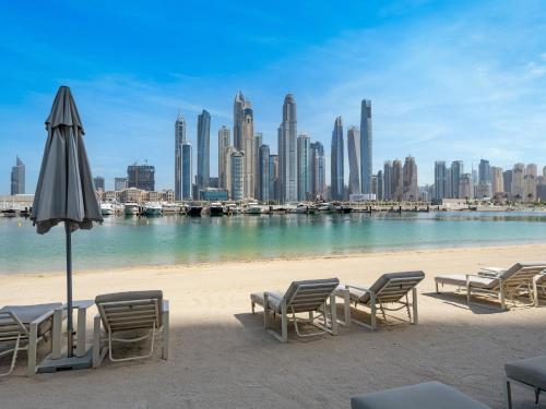 a beach with chairs and an umbrella and a city at Cozy One Bedroom on the Beach in Dubai Harbour - Prestige Retreats in Dubai