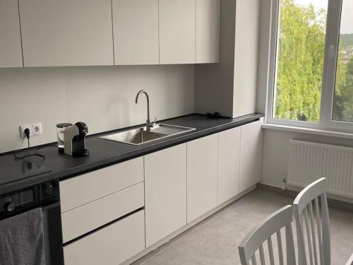 a kitchen with white cabinets and a sink and a window at Chirie apartament in Căuşeni