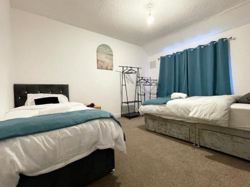1 Schlafzimmer mit 2 Betten und blauen Vorhängen in der Unterkunft Lovely Spacious House Family & Contractor Friendly 3 Bedroom Near Leeds Centre Sleeps 8 in Beeston