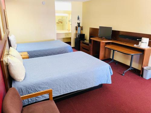 Una habitación de hotel con dos camas y un escritorio con una computadora. en Western Inn Express, en Hazlehurst