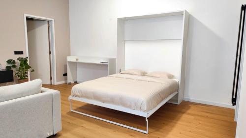 a white bedroom with a bed and a couch at Le Cocon Studio in Brussels